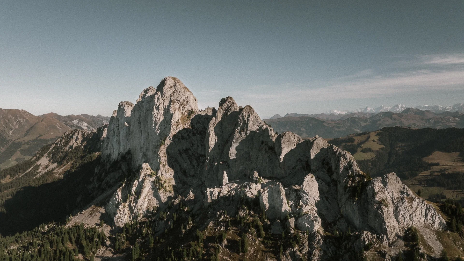 Mountain landscape with rugged peaks, green valleys, and a clear sky.