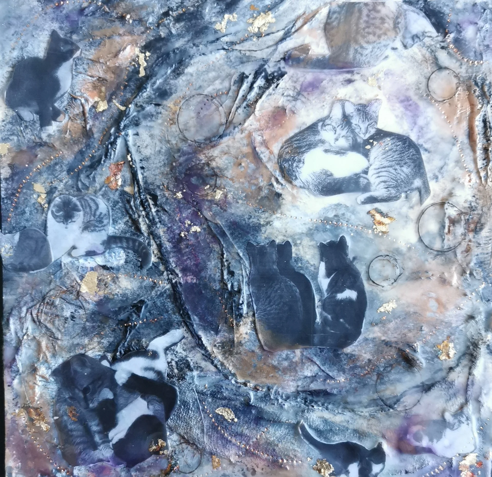 Close-up of an abstract art piece featuring various shades of black, gray, and gold, with circular and textured patterns.