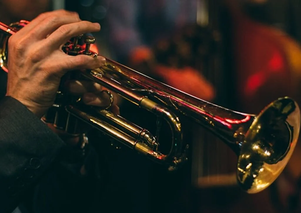 A person playing a brass trumpet.
