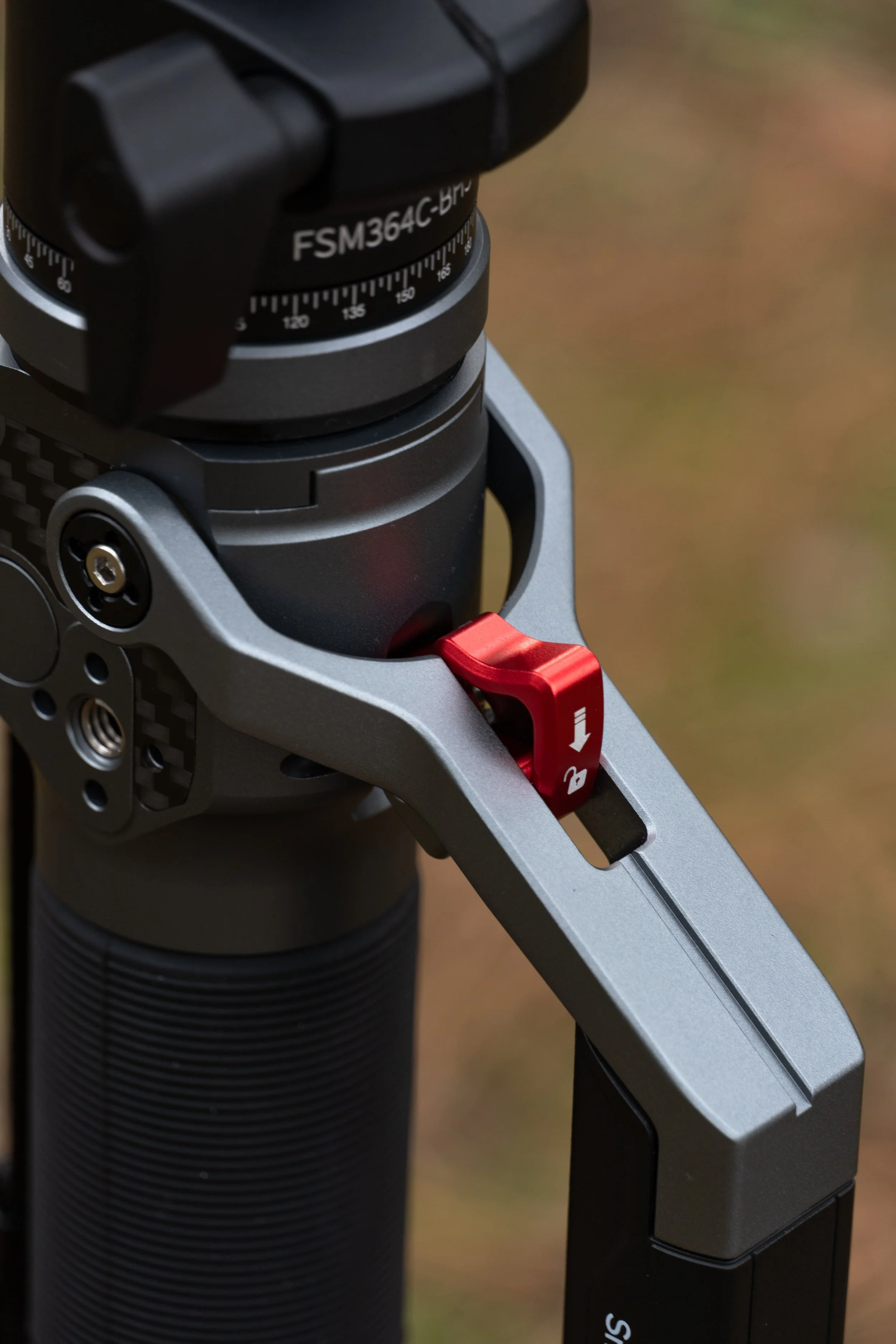 Close-up of a camera gimbal's mounting mechanism with a focus on adjustment dials and a red locking lever.