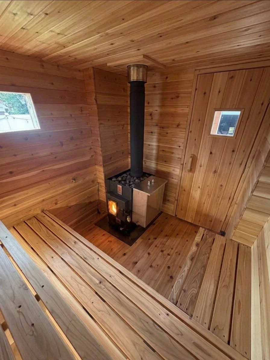 Wood-paneled interior of a small cozy room with a wood stove and small windows.