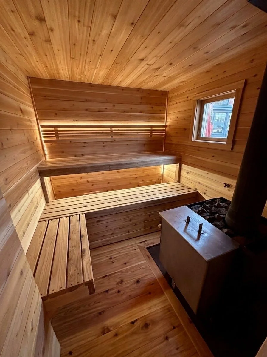 Interior of a cozy wooden sauna with benches and a small window.