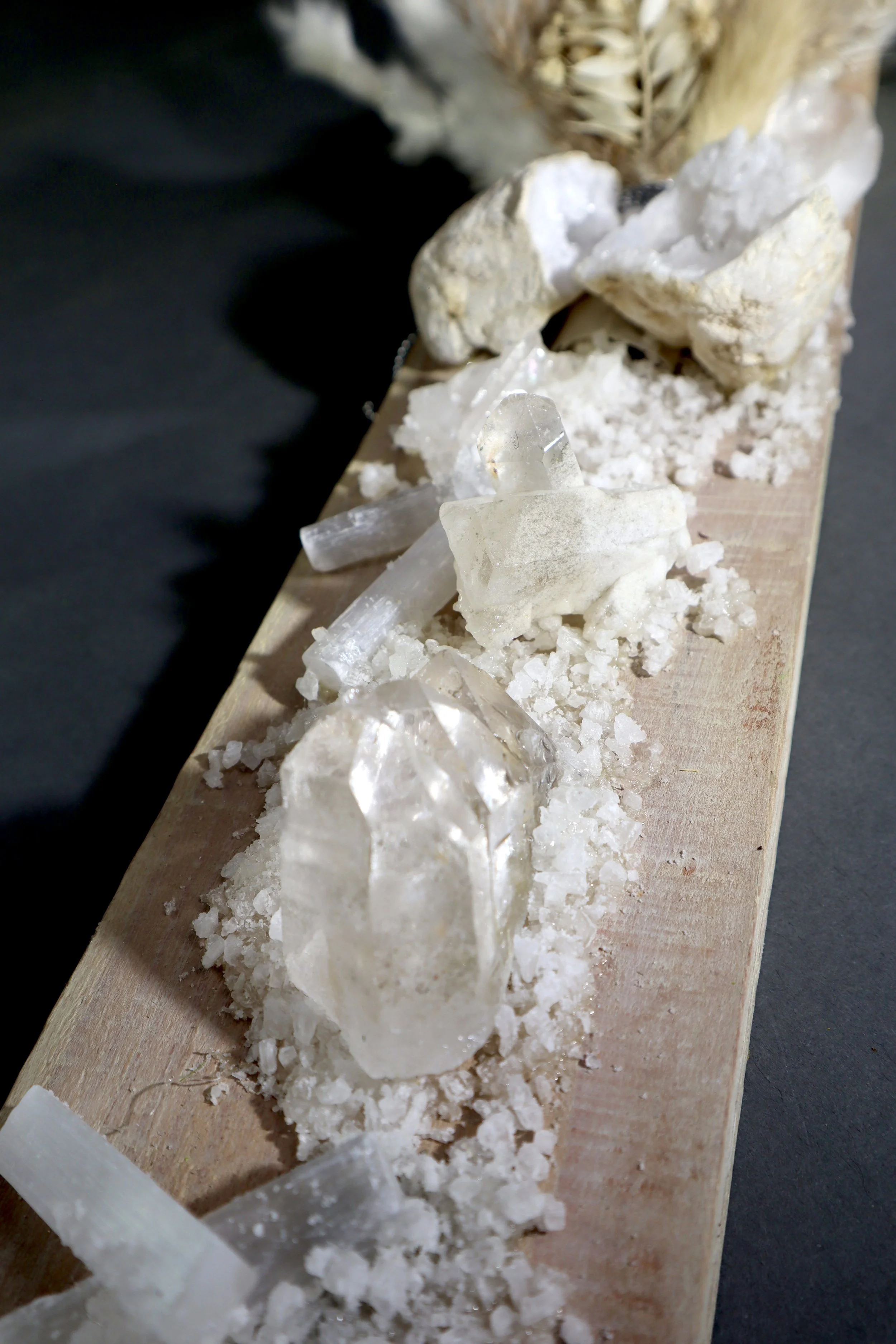 Close-up white mineral wall sculpture with clear quartz, natural stone and dried botanical details