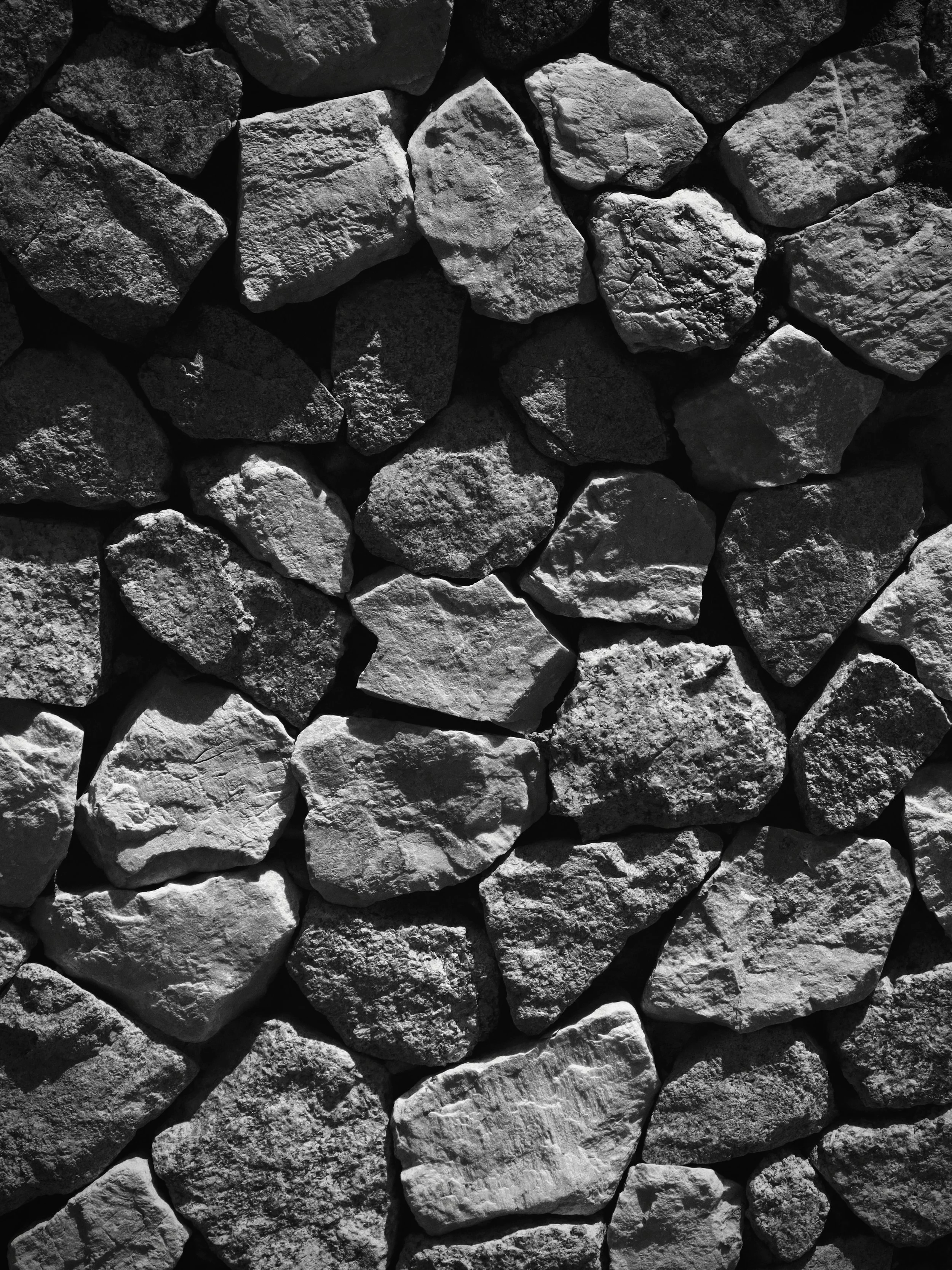 A close-up view of a stone wall composed of irregularly shaped rocks and stones stacked together.