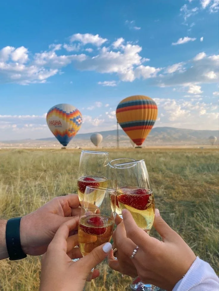 Champagne toast with strawberries as hot air balloons rise at sunrise; Experience.
