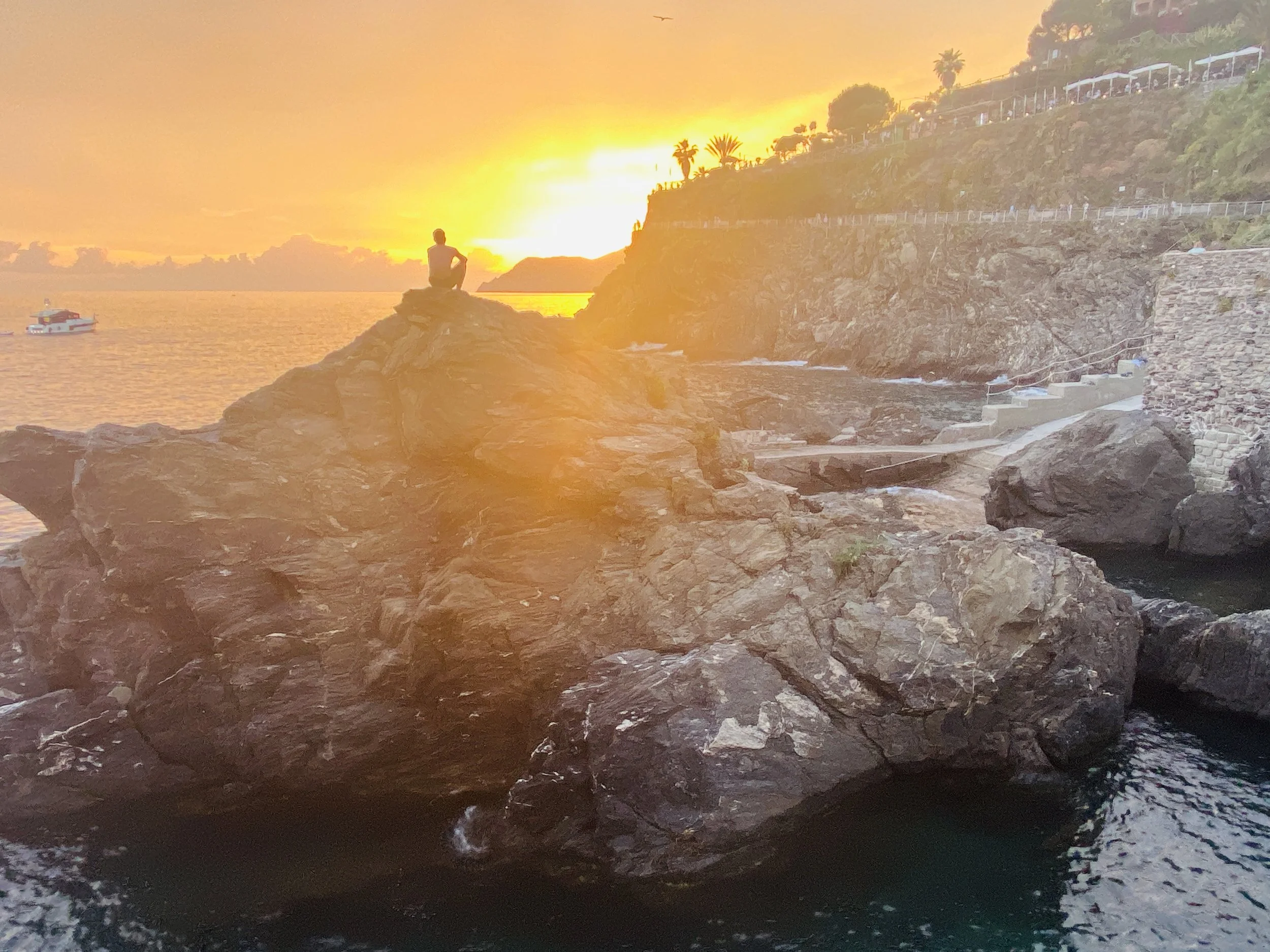Golden sunset over a rocky seaside cliff, captured by travel content creator Tracy of A Curated Passport; Cinque Terre, Italy.