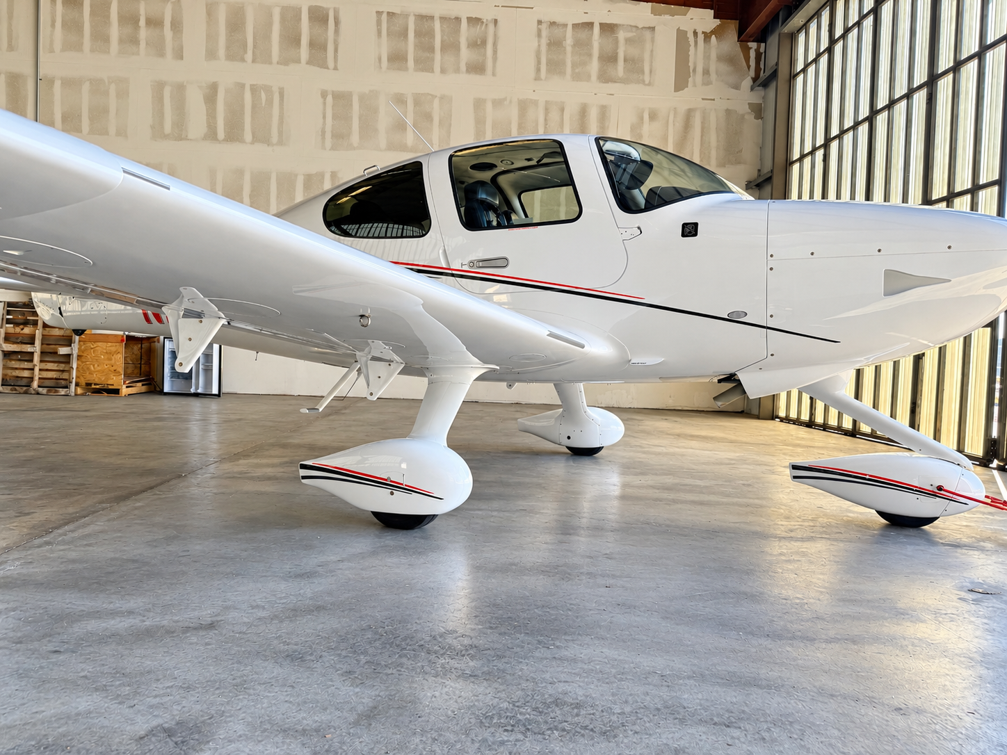 Clean white Cirrus aircraft parked inside a hangar following exterior aircraft detailing