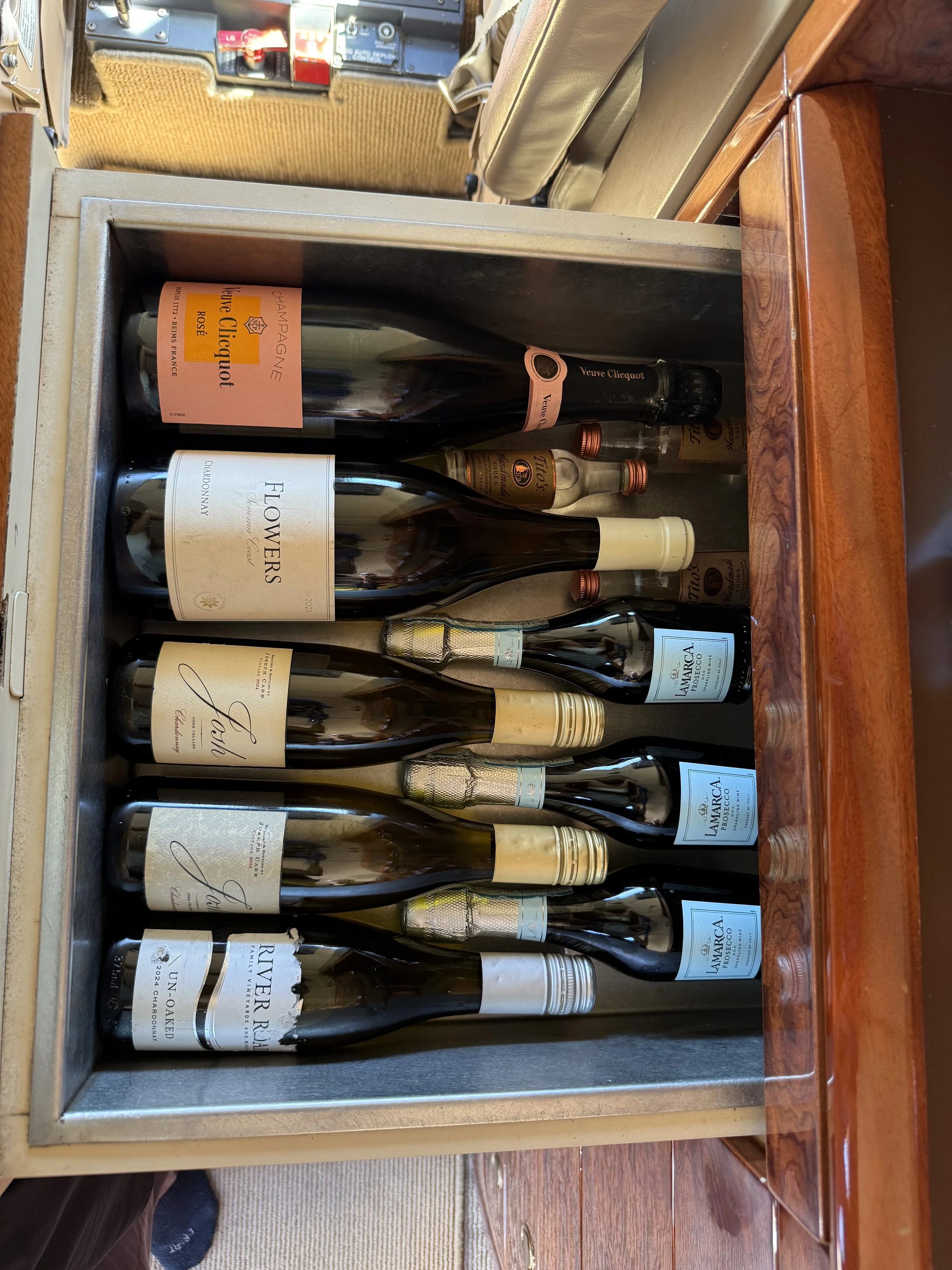 After cleaning: Neatly organized wine and champagne bottles inside the galley storage compartment of a Challenger 604 private jet following interior detailing and cabin organization by San Diego Aircraft Detailers.