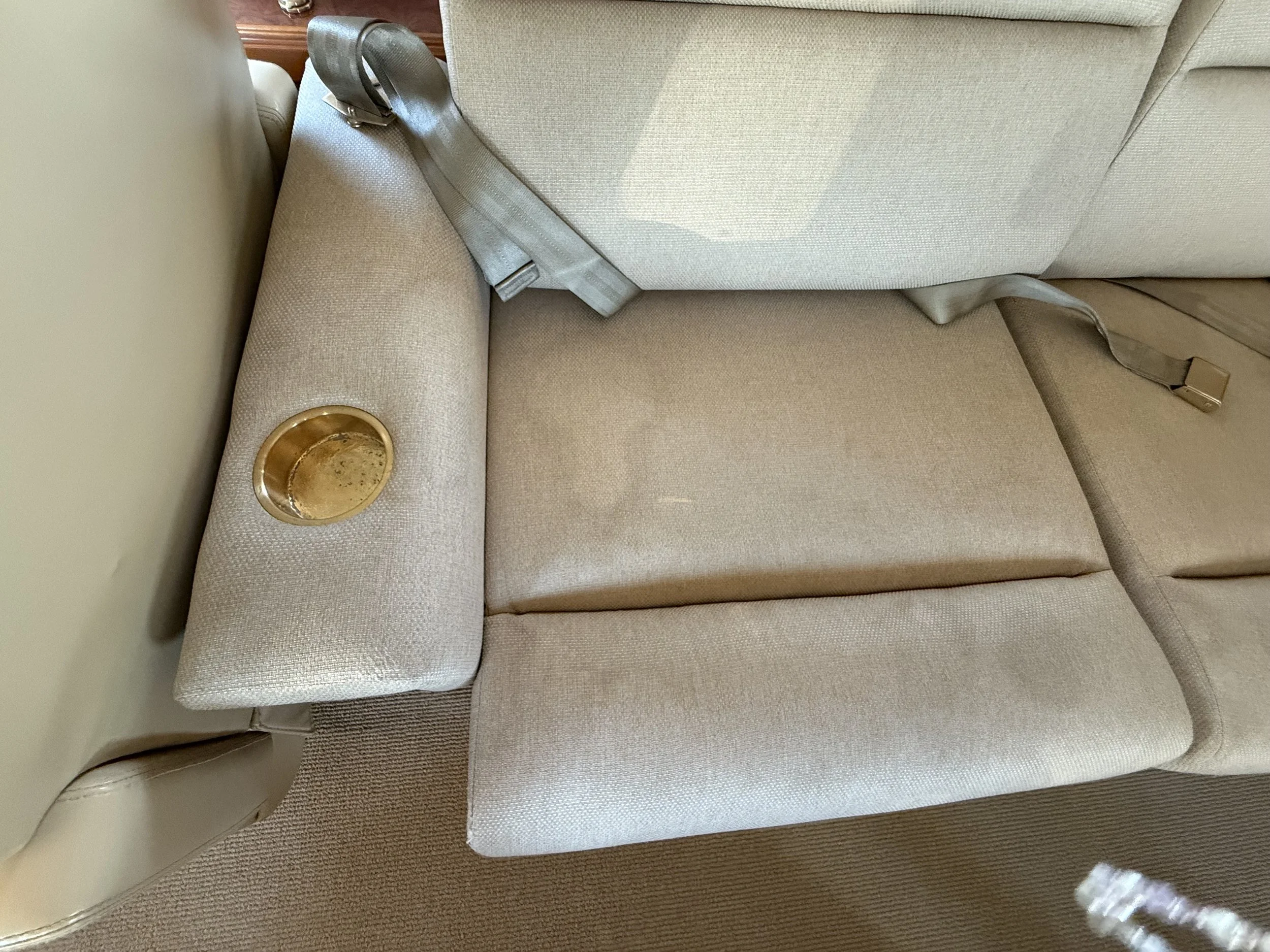 Before cleaning photo of stained beige sofa upholstery inside a Bombardier Challenger 604 at McClellan-Palomar Airport in Carlsbad, CA.