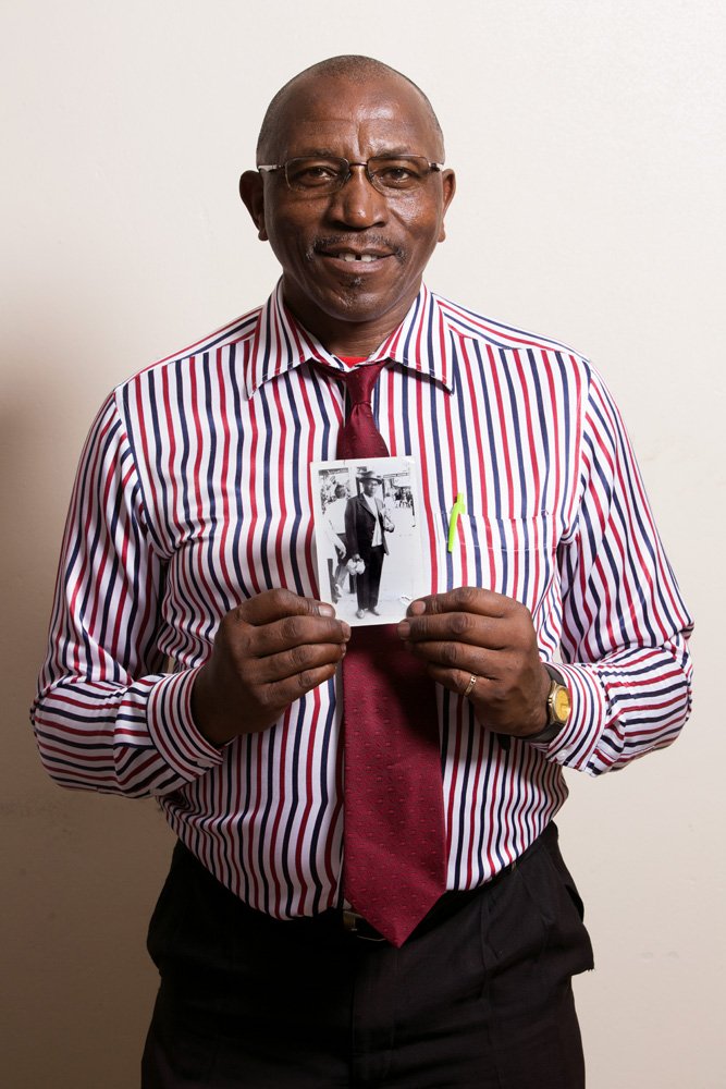 Rethabile Mpalami holds an analog black-and-white photo of his father Solomon. Solomon worked as a manager in the mines in Soweto. Mr. Mpalami has been a maths teacher since 1978. He works at the Nteboheng Primary School in Botshabelo. (Botshabelo, F