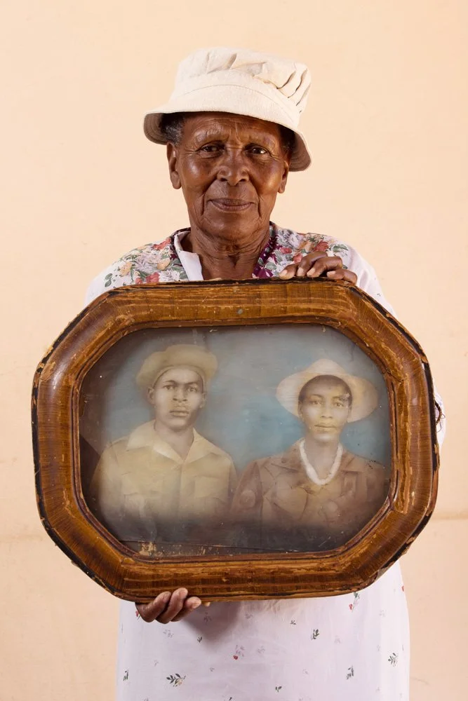 Adelina Seboilwe Dibe holds a framed hand-coloured portrait of her parents, Zacharia Majawetsa and Anne M'Chopi. The photo was made in the late 1930's. Mrs. Majawetsa worked at home and raised Adelina and her two sisters while her husband served in t