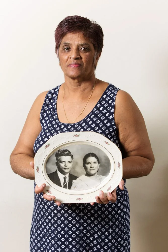 Ann Naidu holds a black-and-white portrait of her parents Rama and Lutchmee, printed on a porcelain plate. Mrs. Naidu works as a sales clerk. (Westdene/Bloemfontein, Free State).