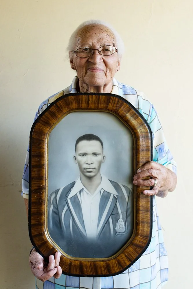 Delores Maritz, holding a framed, hand-coloured portrait of her husband as a young man. (Heidedal/Bloemfontein, Free State).