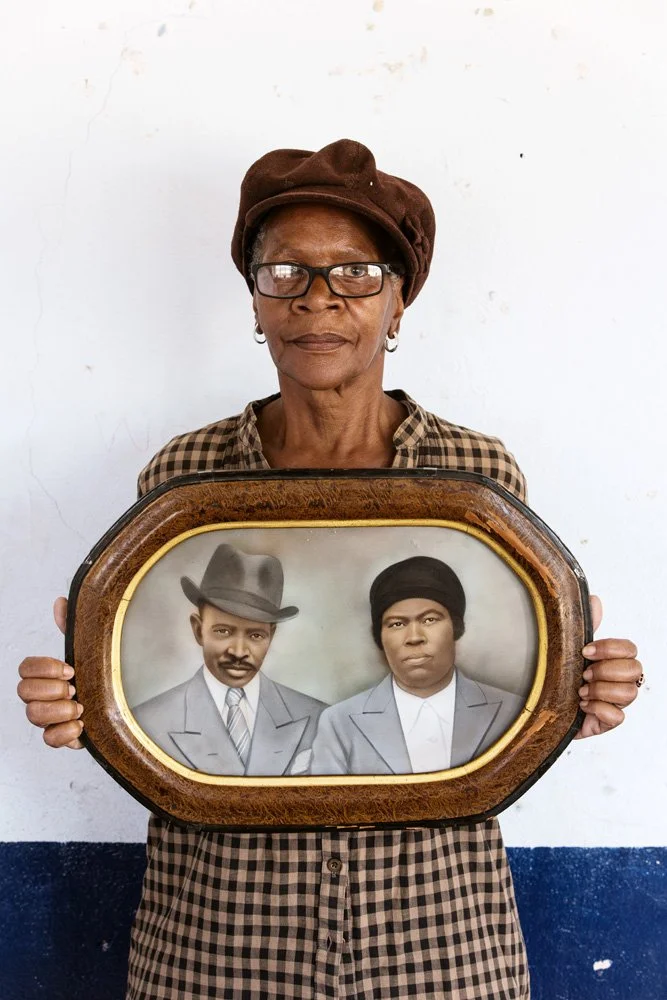 An unidentified member of the Tshwaranang Ladies' Luncheon Club holds a framed, hand-coloured black-and-white portrait of her parents. (Batho Location/Bloemfontein, Free State).