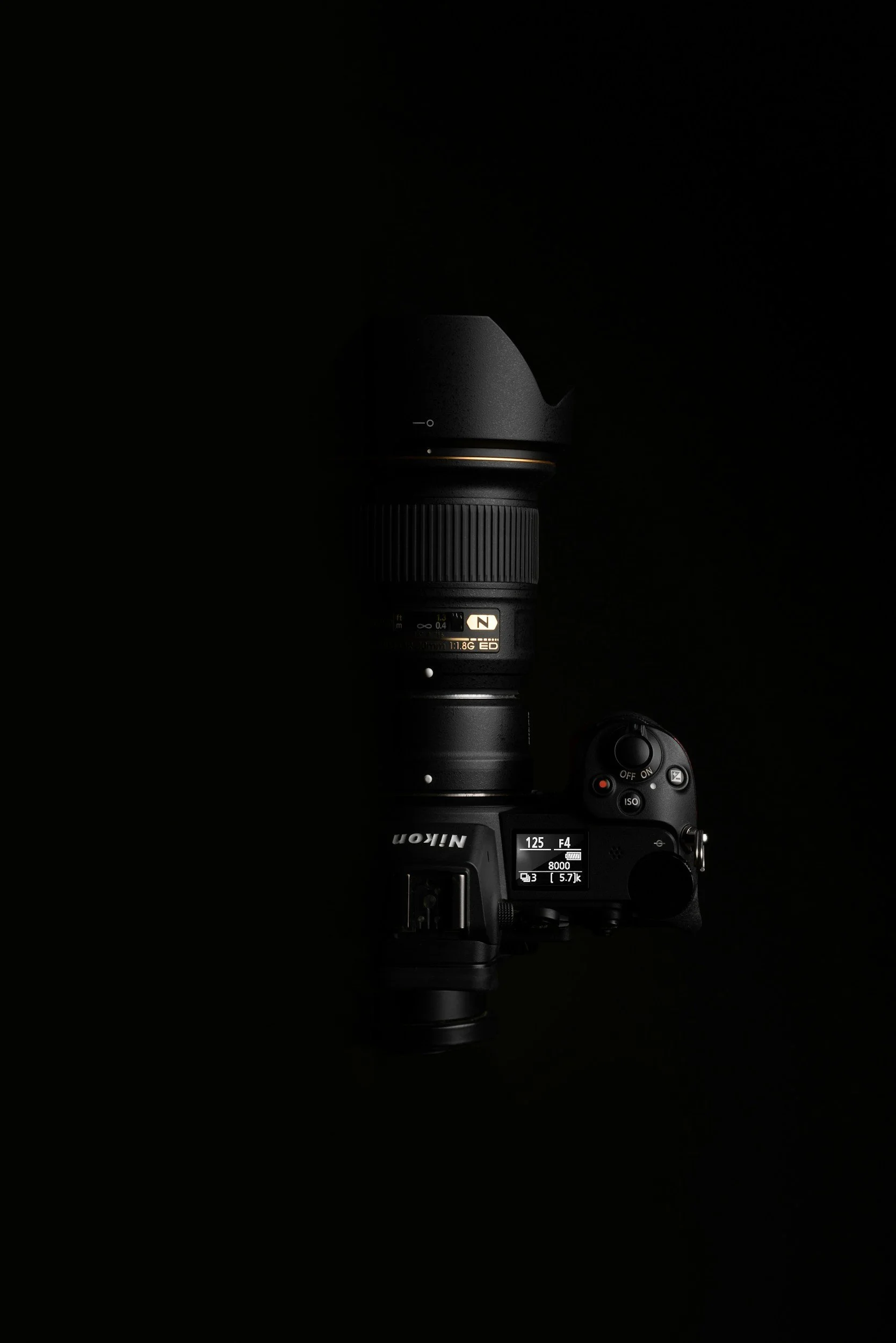 A digital camera with a large zoom lens mounted on a camera body, displayed against a black background.