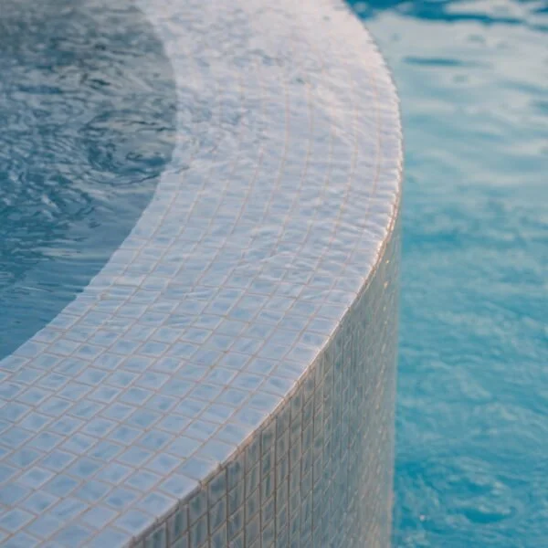 Close-up of a curved tiled pool edge surrounded by blue water