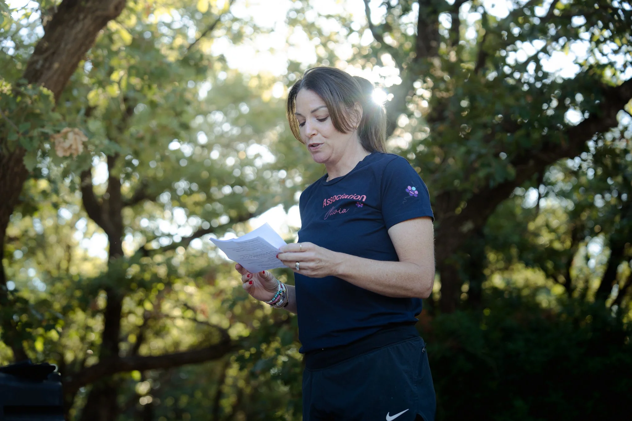Femme en tenue de sport lisant un papier en plein air, avec des arbres en arrière-plan