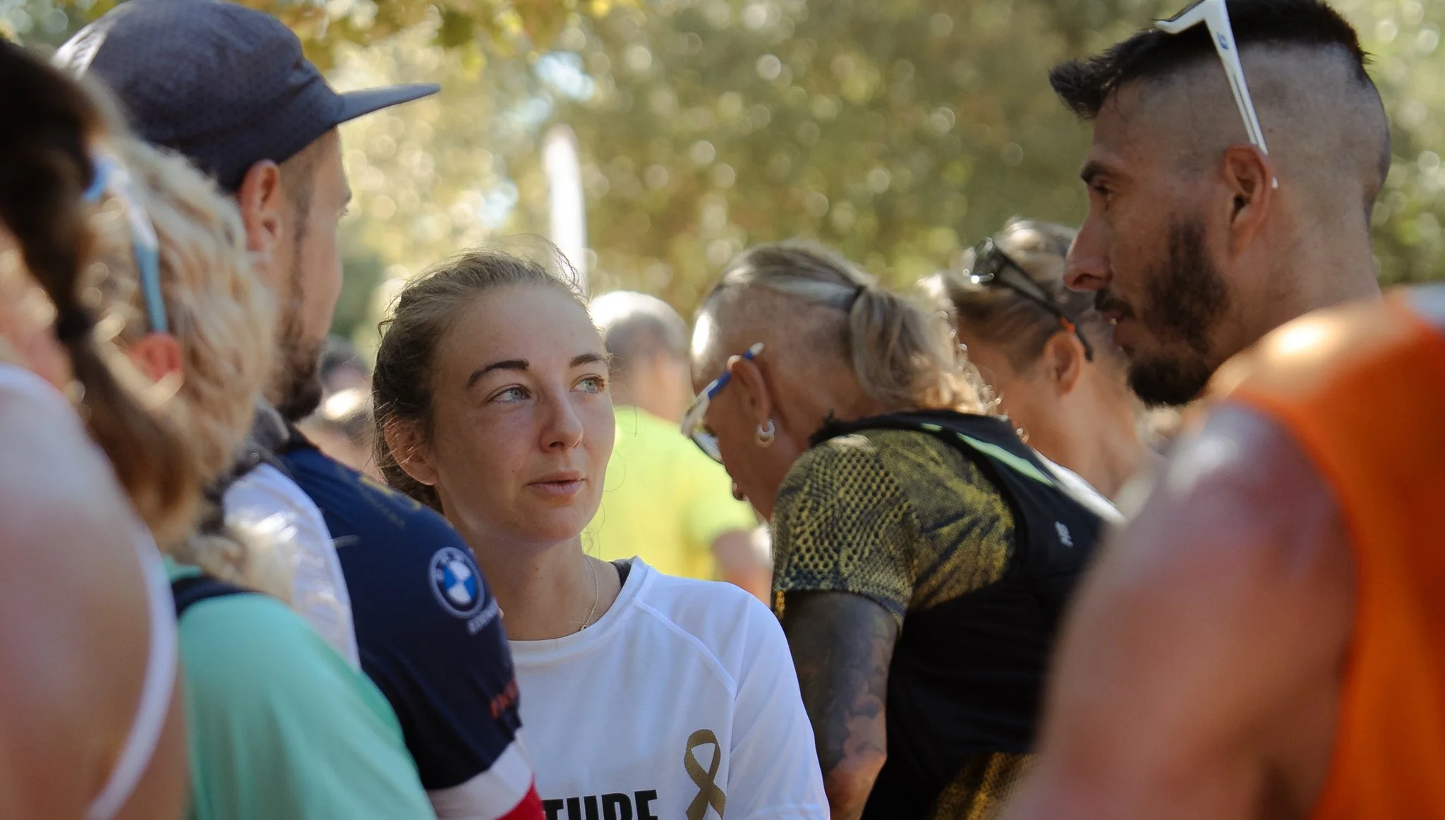 Groupe de personnes en conversation dans un parc lors d'un événement sportif ou social.