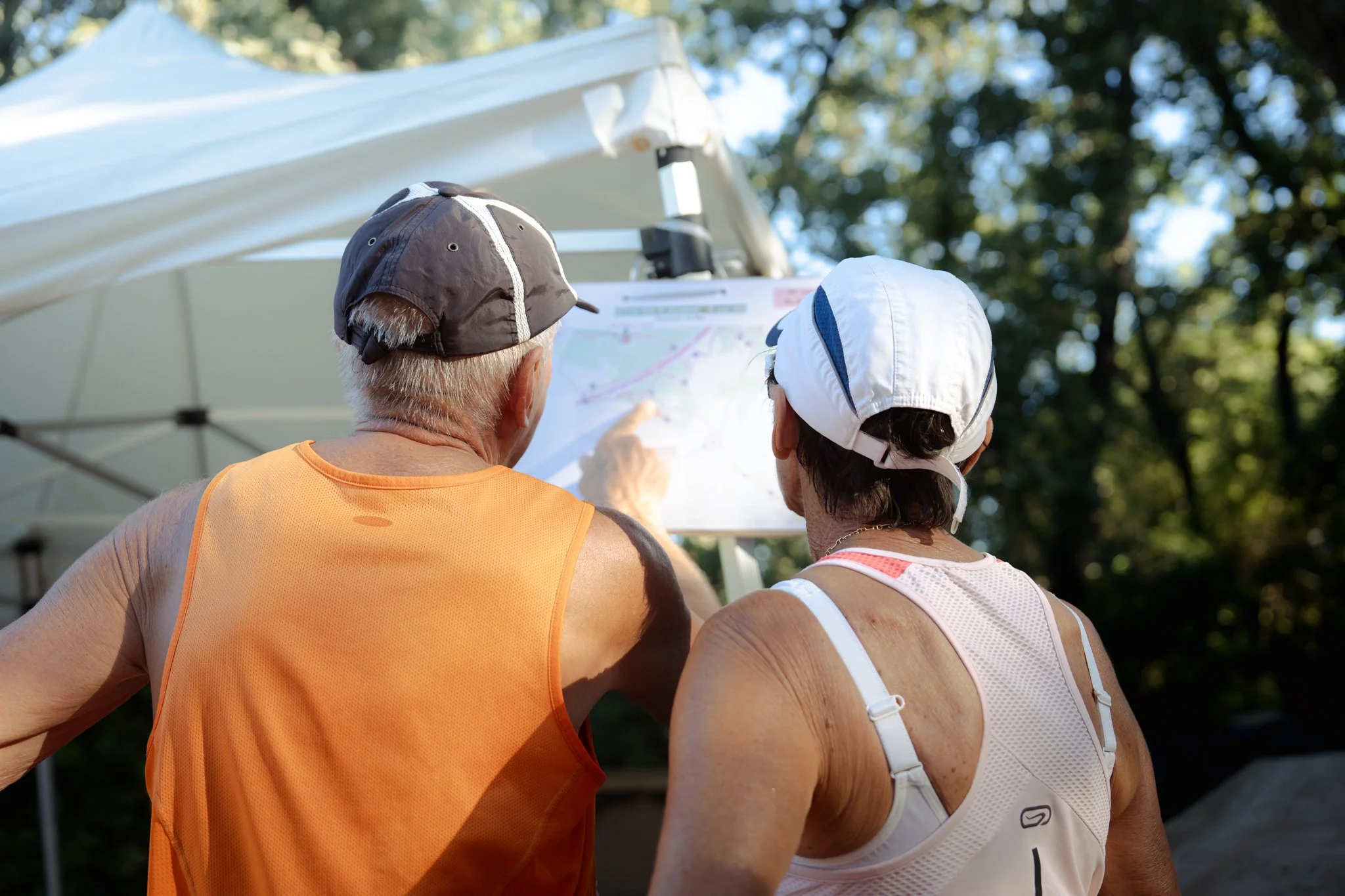 Deux personnes regardant une carte sous un parasol lors d'une activité en extérieur.