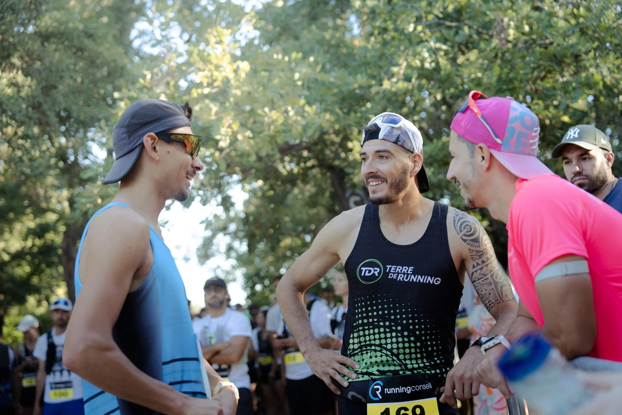Groupe de coureurs en tenue de sport discutant avant une course en plein air, avec des arbres en arrière-plan.