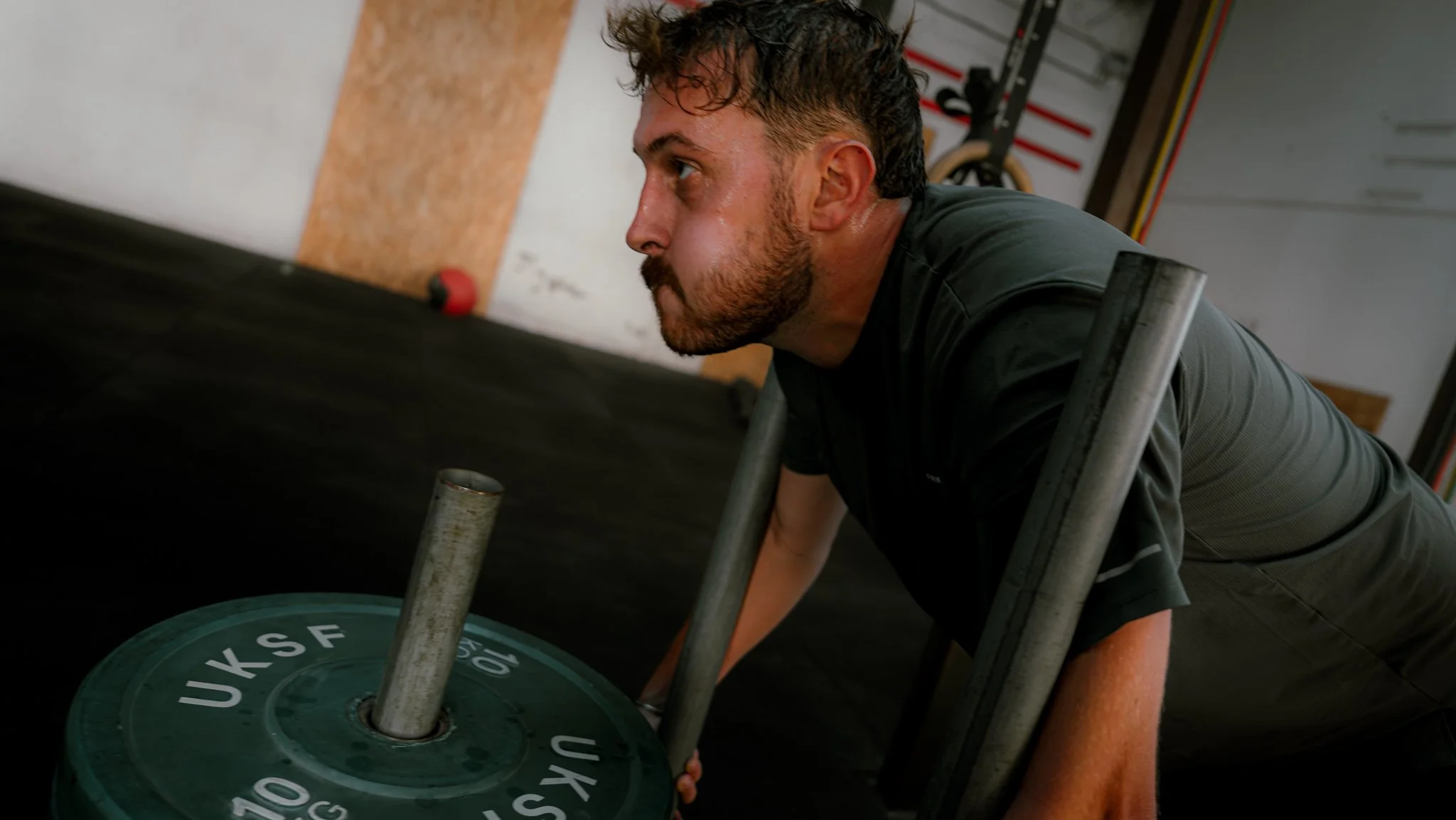 Un homme en train de faire de l'exercice avec une barre de musculation dans une salle de squat.