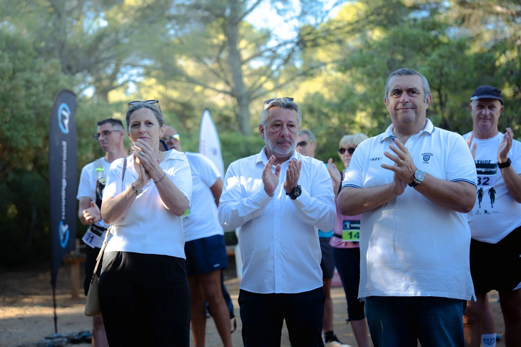 Groupe de personnes participant à une activité en plein air, applaudissant, dans un parc entouré d'arbres en automne.
