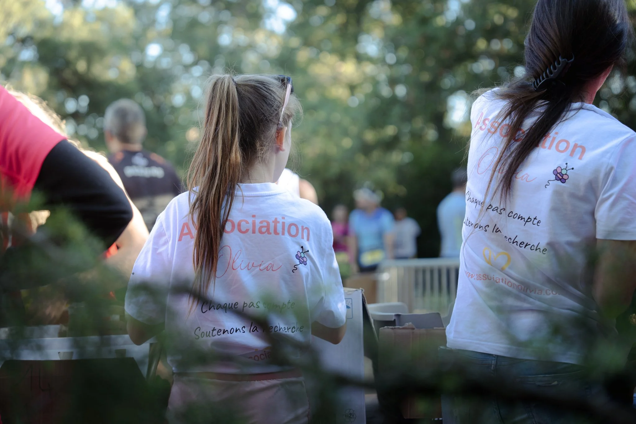 Groupe de personnes portant des t-shirts blancs lors d'un événement en plein air, avec un arbre en arrière-plan.
