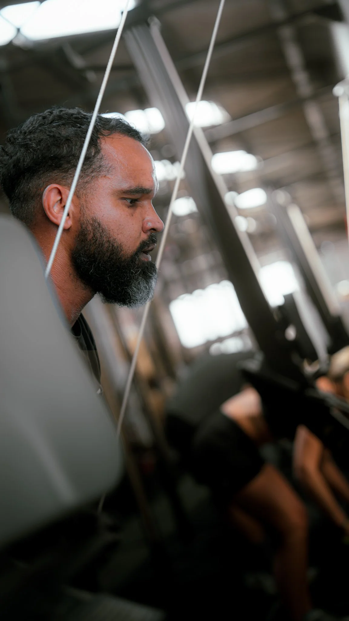 Homme avec barbe concentré sur un ordinateur dans un environnement industriel ou technologique