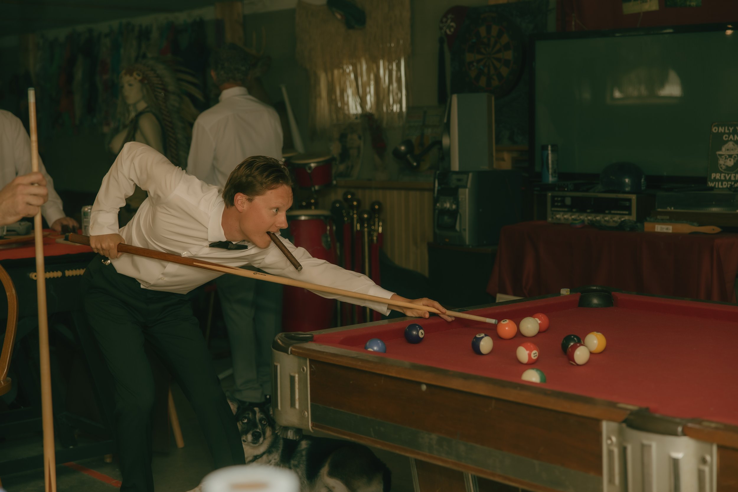 Groom playing pool while getting ready on his wedding day