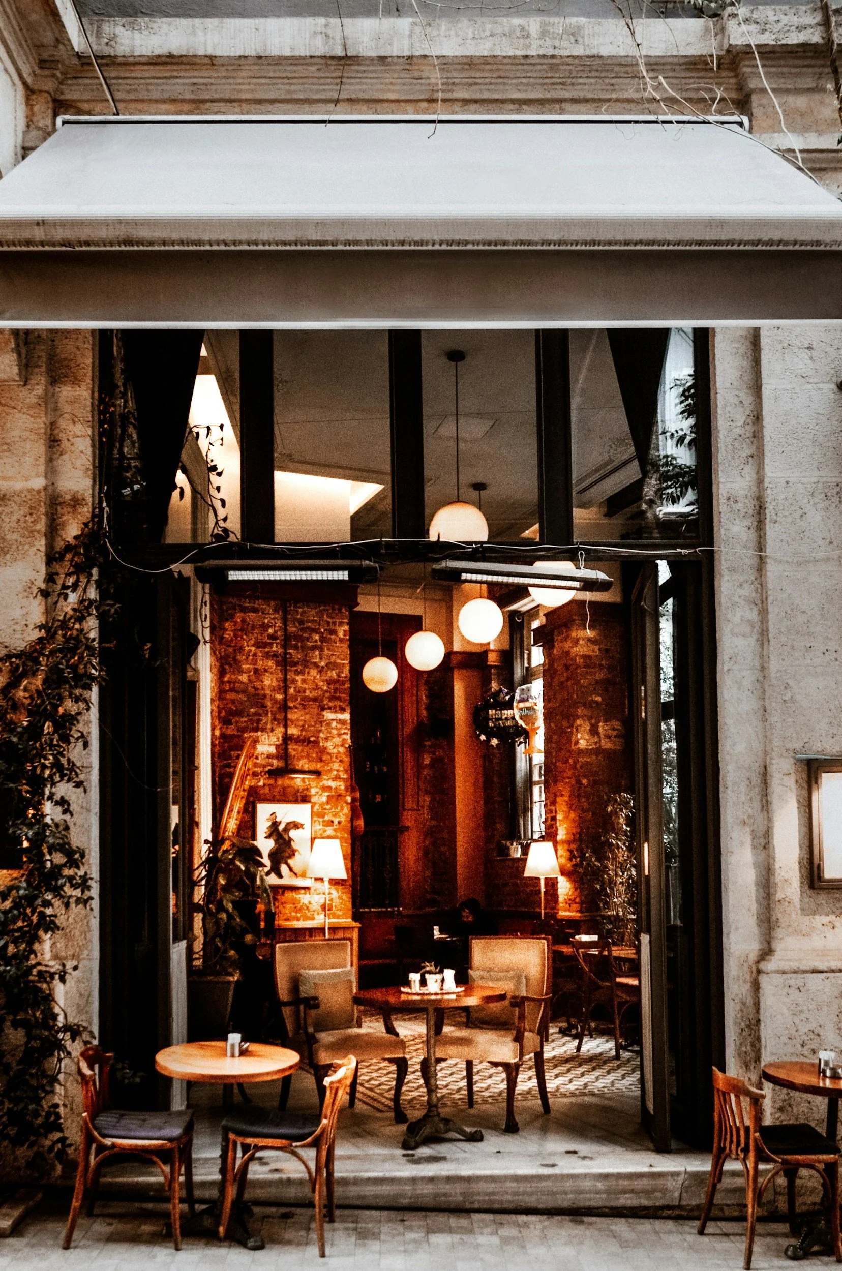Innenraum eines Cafés mit Tischen, Stühlen, warmem Licht, Ziegelwand und dekorativen Elementen