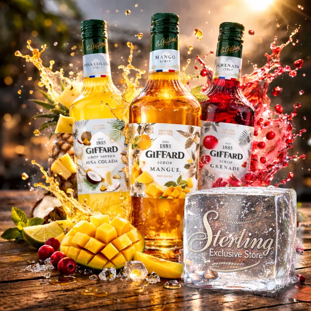 Drei Flaschen Giffard Sirup mit Fruchtgeschmacksrichtungen Ananas, Mango und Granatapfel, umgeben von Früchten und Eiswürfeln, mit Spritzern von Flüssigkeiten, auf einem Holzoberfläche, im Hintergrund eine bewaldete Szenerie mit Sonnenlicht.