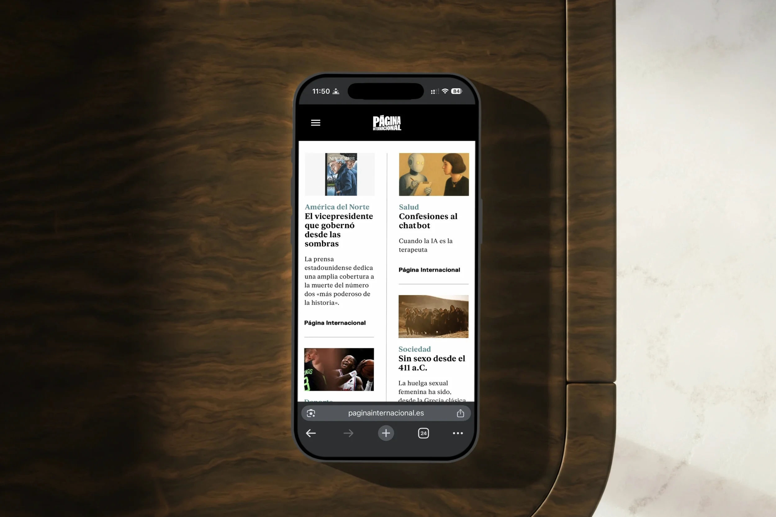 A smartphone displaying Página Internacional website on a wooden table surface.
