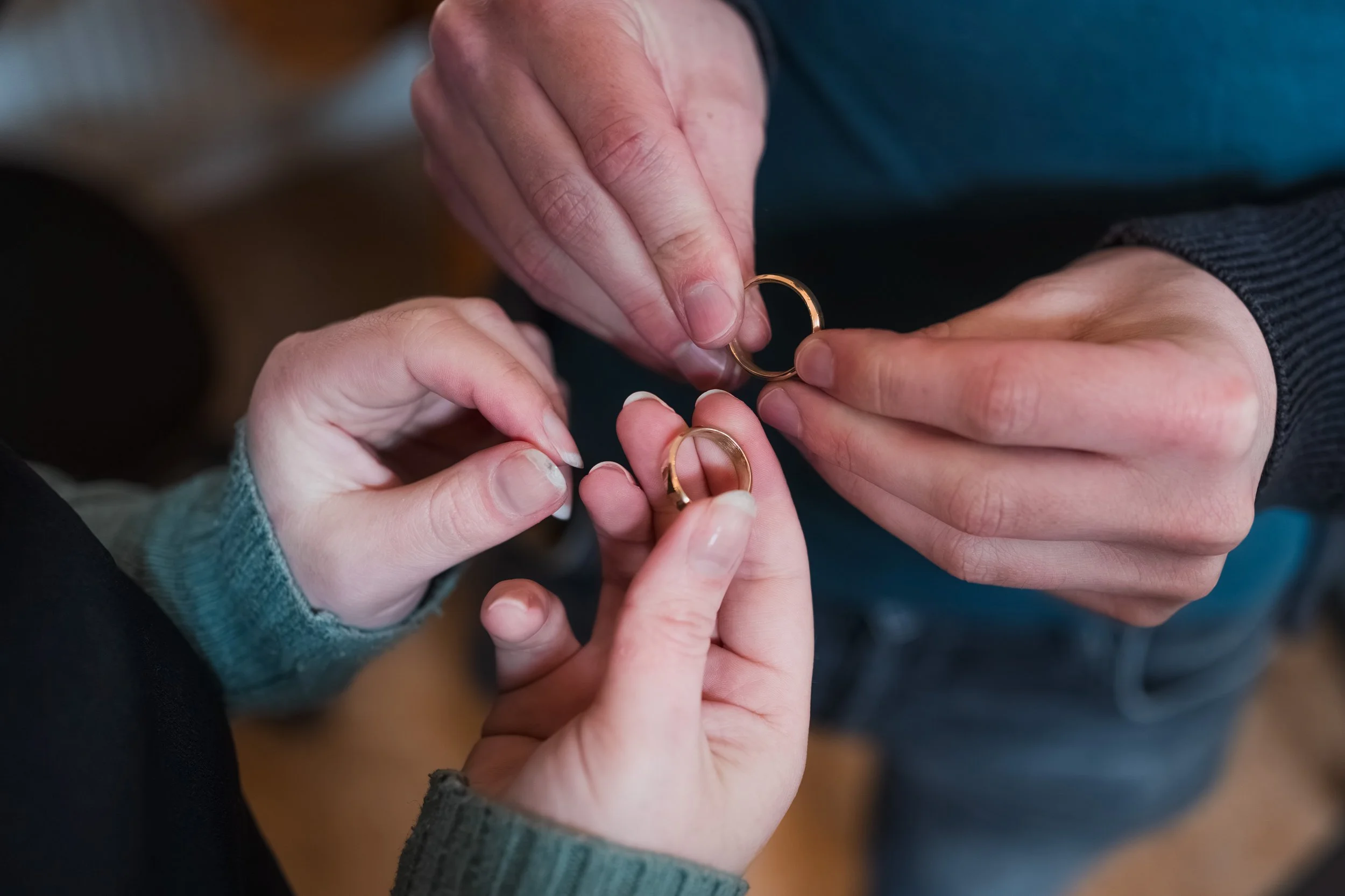 Zwei Personen tauschen Ringe aus. Nahaufnahme der Hände mit goldenen Ringen.