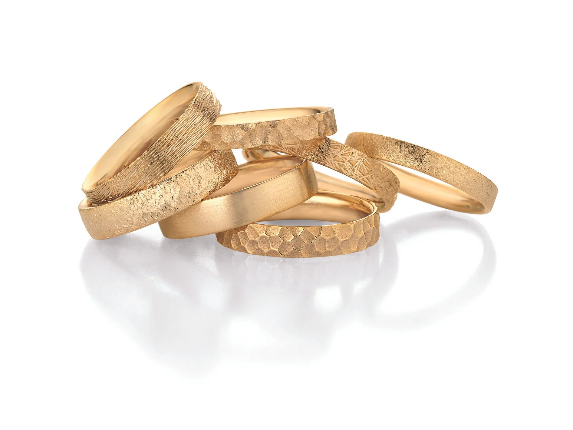 Mehrere goldene Ringe mit verschiedenen Strukturen und Texturen die die Vielfalt und die Individualisierung von Trauringen zeigen die das Brautpaar eigens gestallten kann