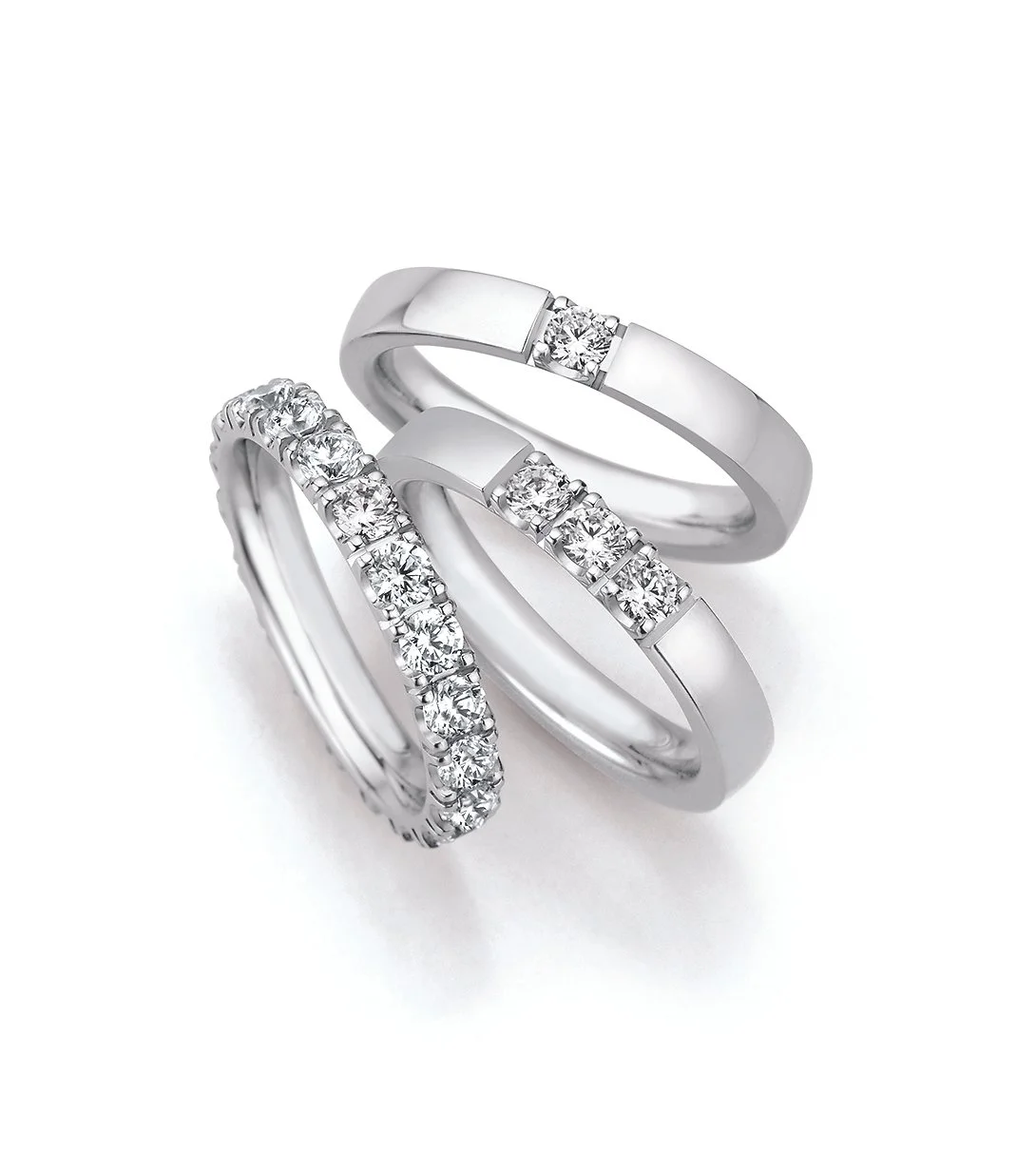 Drei silberne Ringe mit Diamanten, zwei mit Steinen besetzt und einer mit einem einzelnen Diamanten als Geschenk zur Hochzeit oder zur Verlobung
