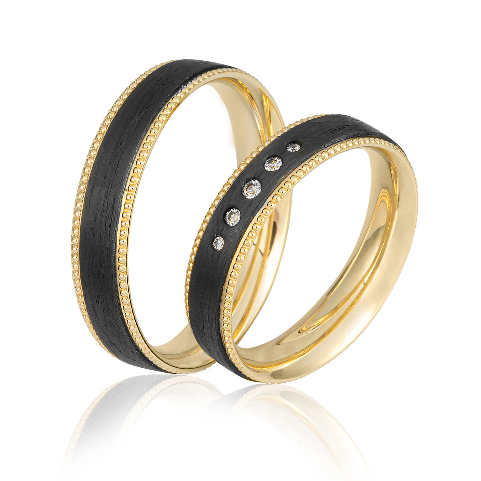 Nahaufnahme von drei goldenen Ringen mit schwarzen und mit Diamanten besetzten Elementen, spiegelnd auf weißem Hintergrund.
