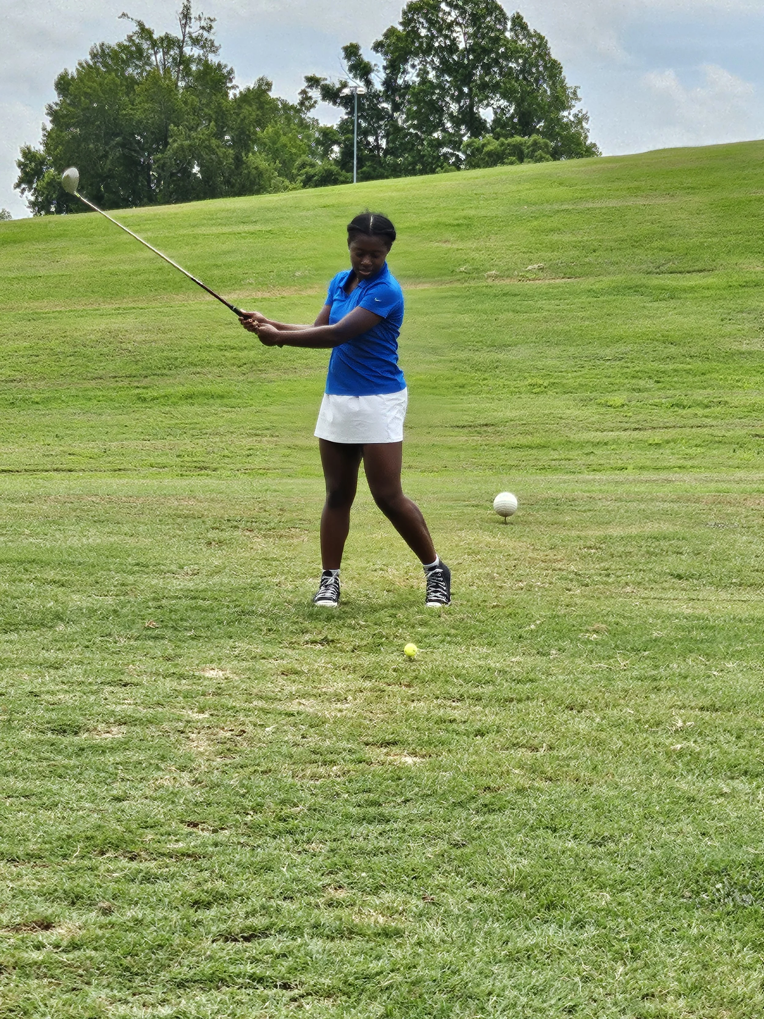 Michal Wilburn swinging a golf club; soccer forward