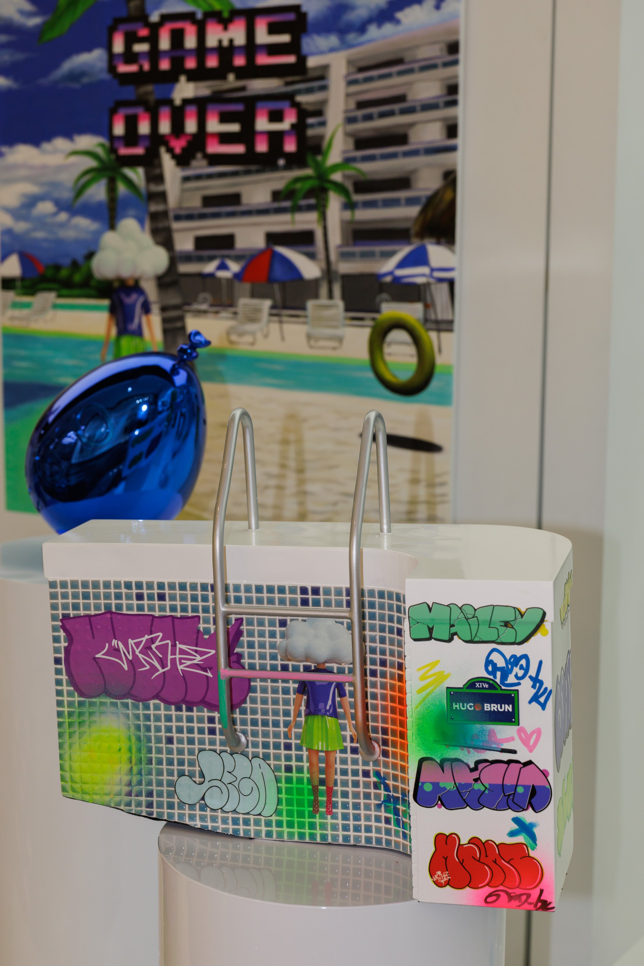 A colorful arcade game with graffiti art and stickers on the side, featuring graffiti-style text and a figurine of a girl in green. The background depicts a beach scene with a hotel and umbrellas.