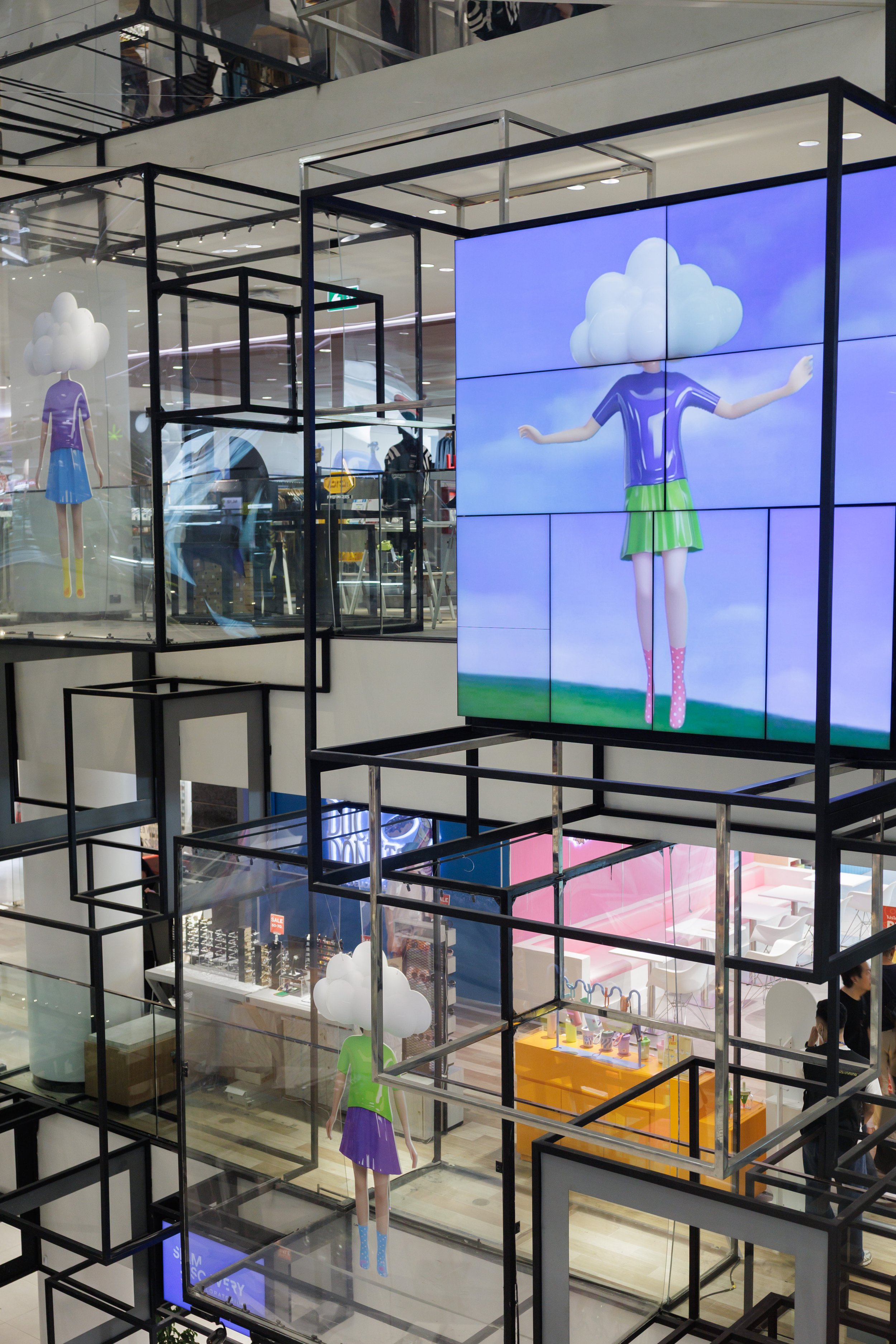 Store display featuring mannequins with cloud-shaped heads, colorful clothing, and digital screens showcasing similar cloud-themed imagery.
