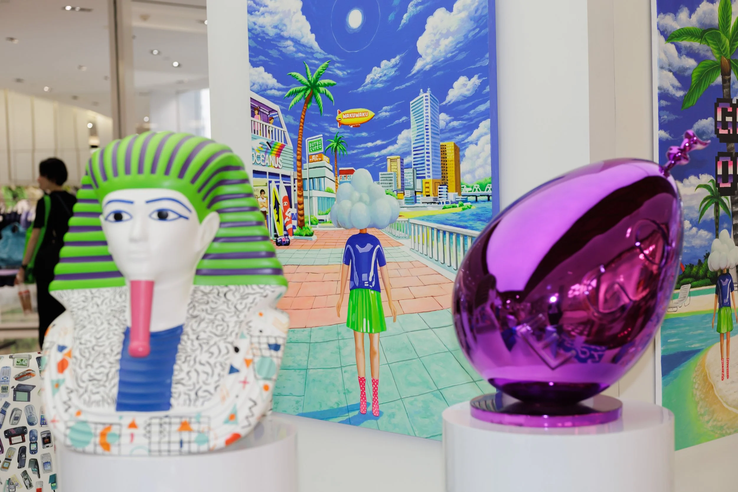 Colorful pop art scene with cartoon-like characters and vibrant background featuring a cityscape, palm trees, and a blue sky with clouds.