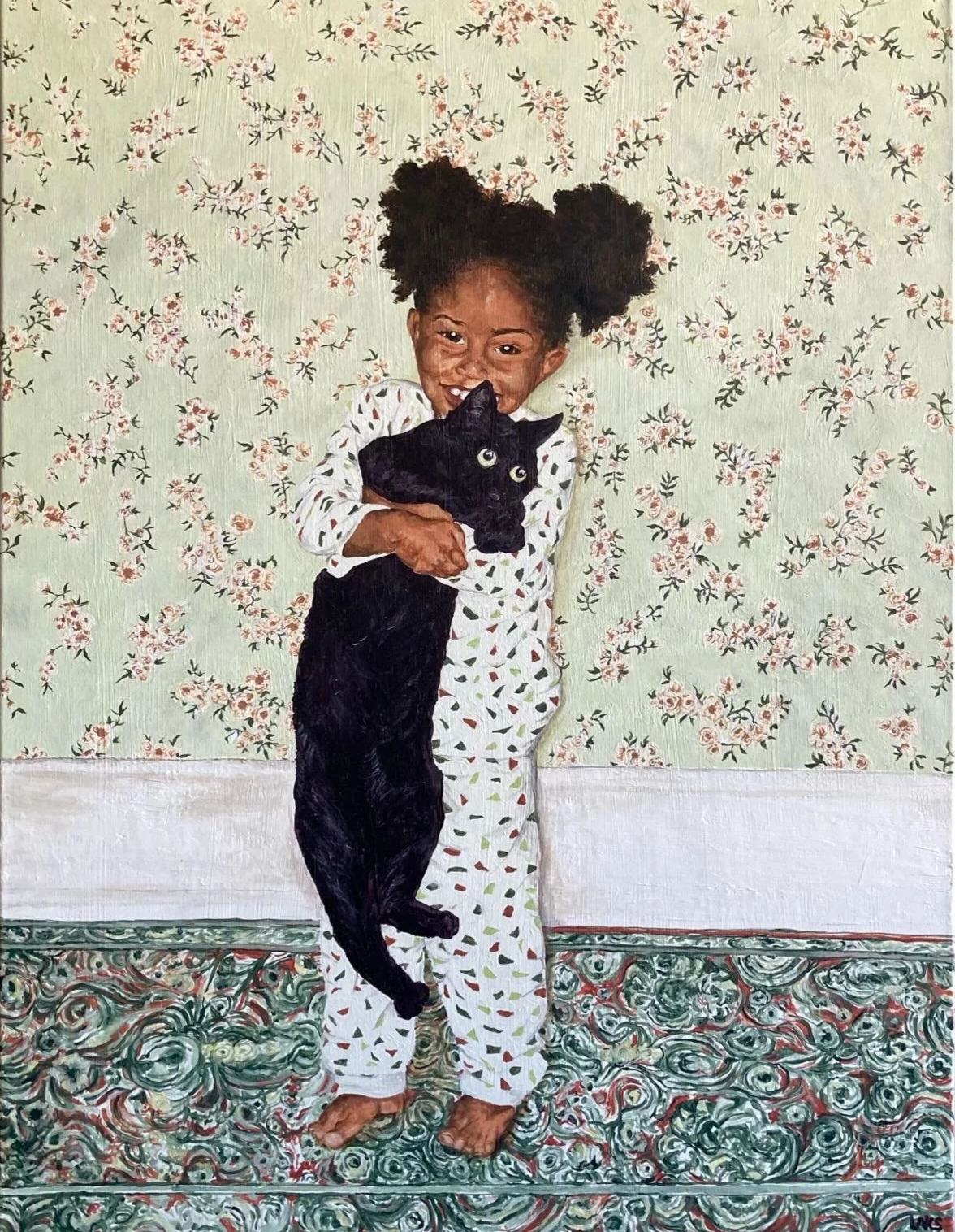 A young girl with curly hair styled in puffs, dressed in pajamas with a colorful triangle pattern, stands on a decorative patterned rug in front of floral wallpaper. She is smiling and holding a black cat with yellow eyes, which also appears to be sm