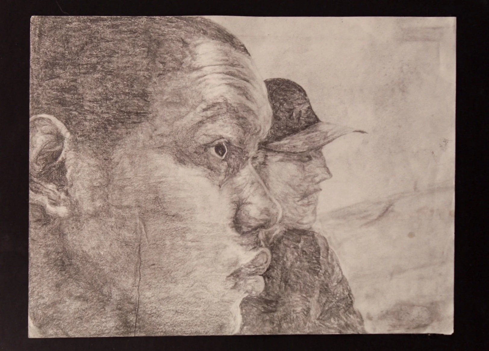 A detailed pencil sketch of three faces in profile, overlapping each other, with a neutral background.