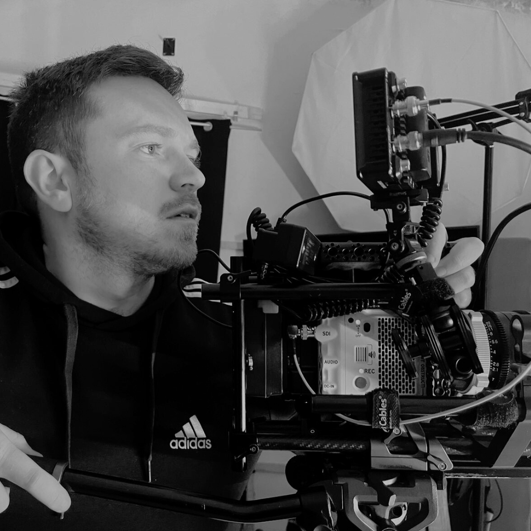 A man operating a professional video camera setup in a studio.