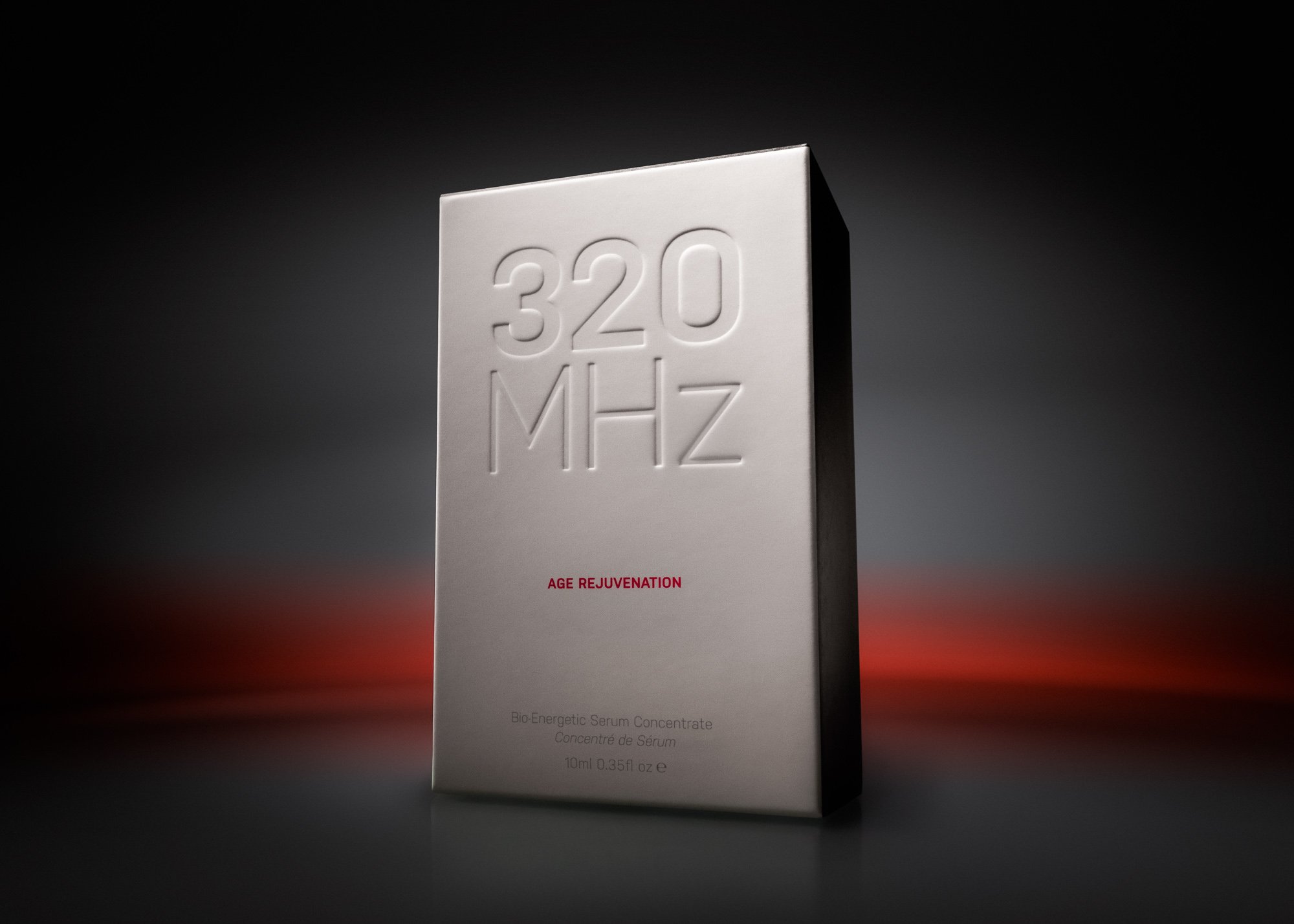Packaging box for a skincare product called 'AGE REJUVENATION'. The box is white with embossed numbers '320' and letters 'MHZ' on the front. The background is dark, and the bottom part of the box features small text indicating it is a bio-energetic s