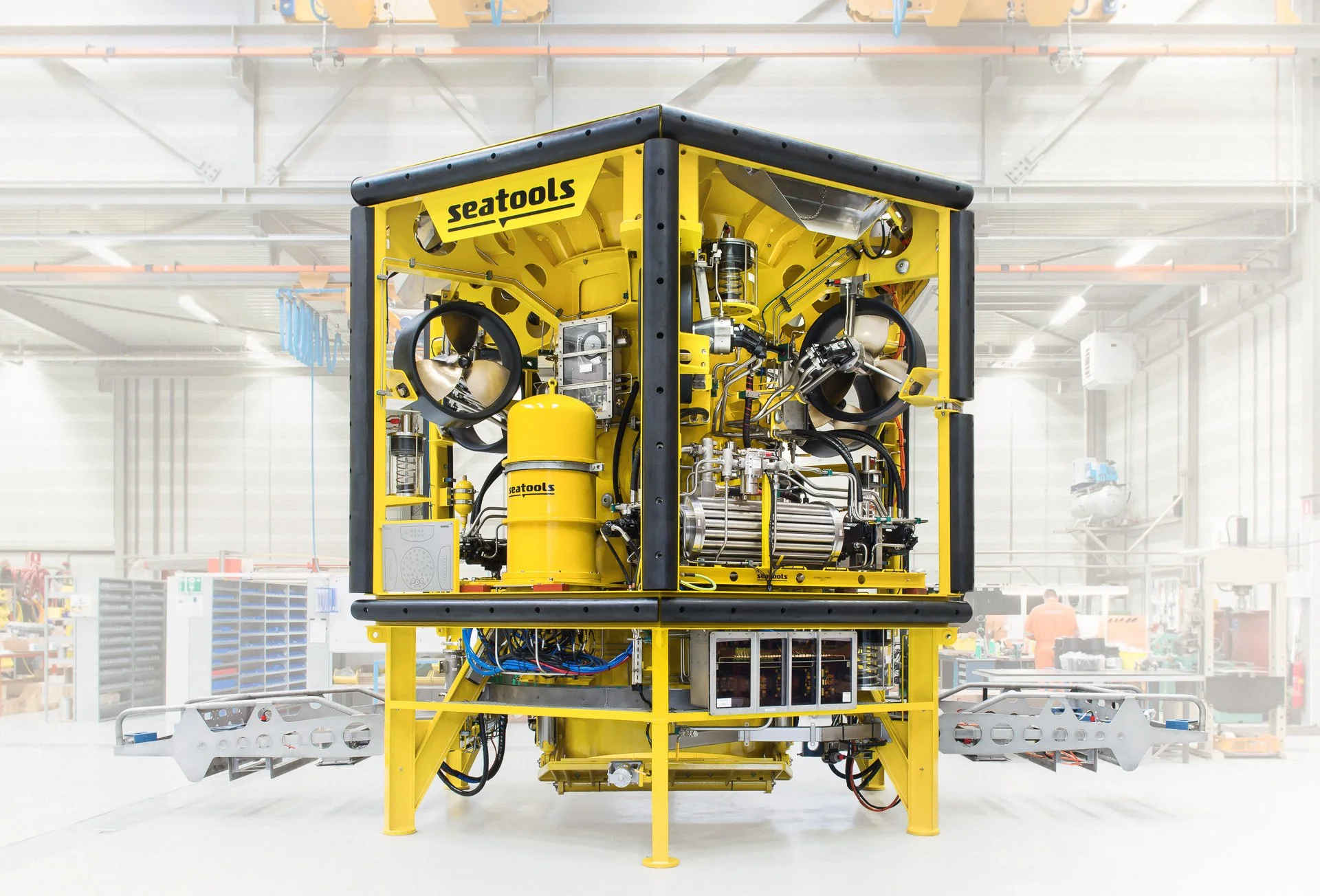 Yellow robot with mechanical arms and components in a factory or laboratory setting.