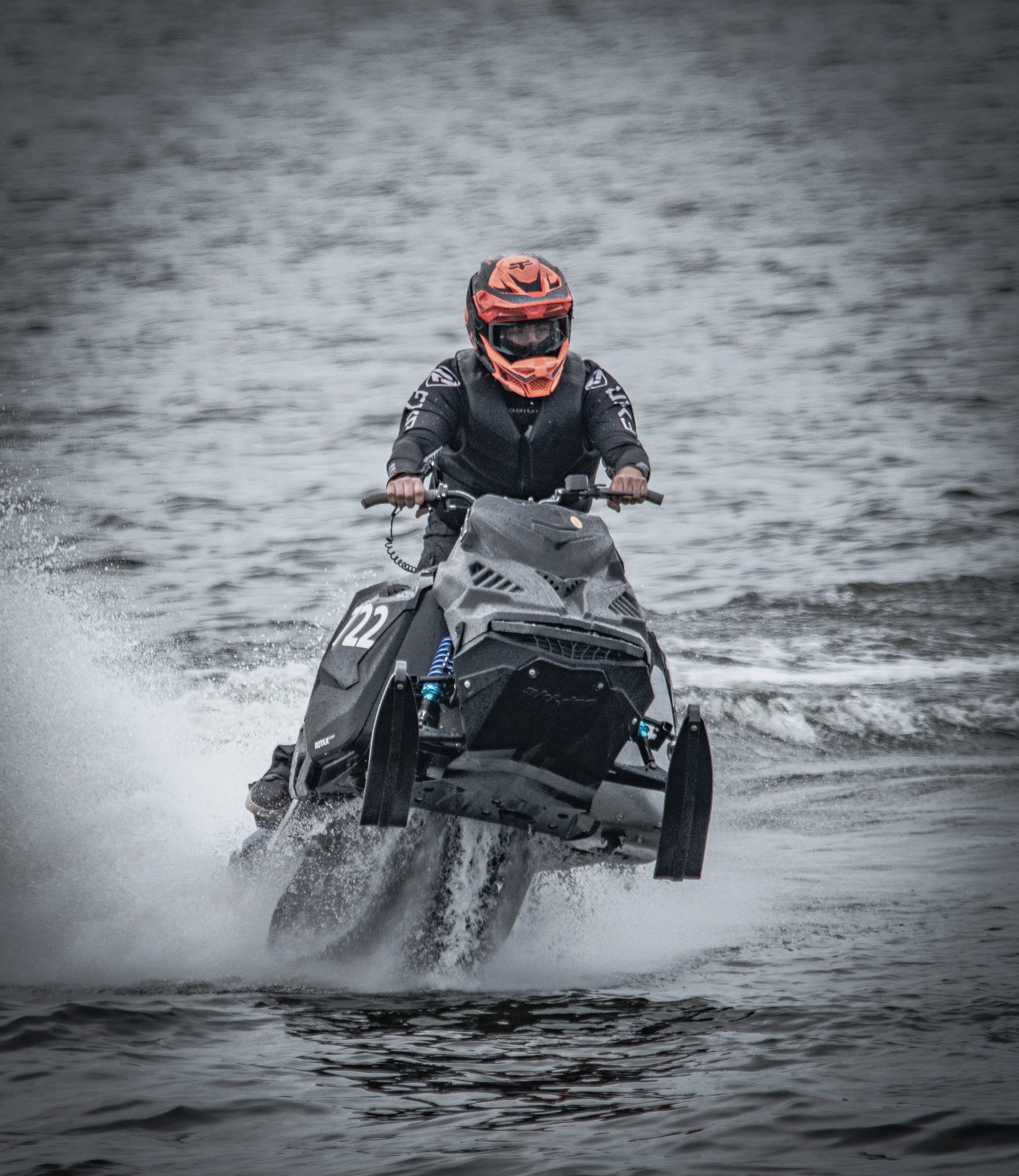 Snowmobile splashdown action photo in Tweed, Ontario. Rider in helmet and riding gear doing some watercross racing for OWRA.