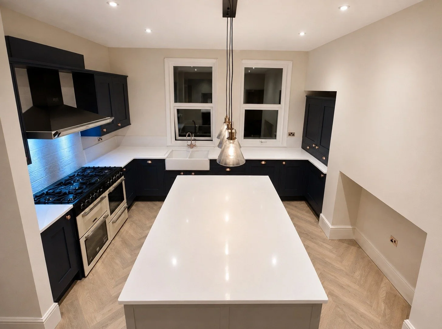 Stylish navy kitchen with a spacious island and herringbone flooring