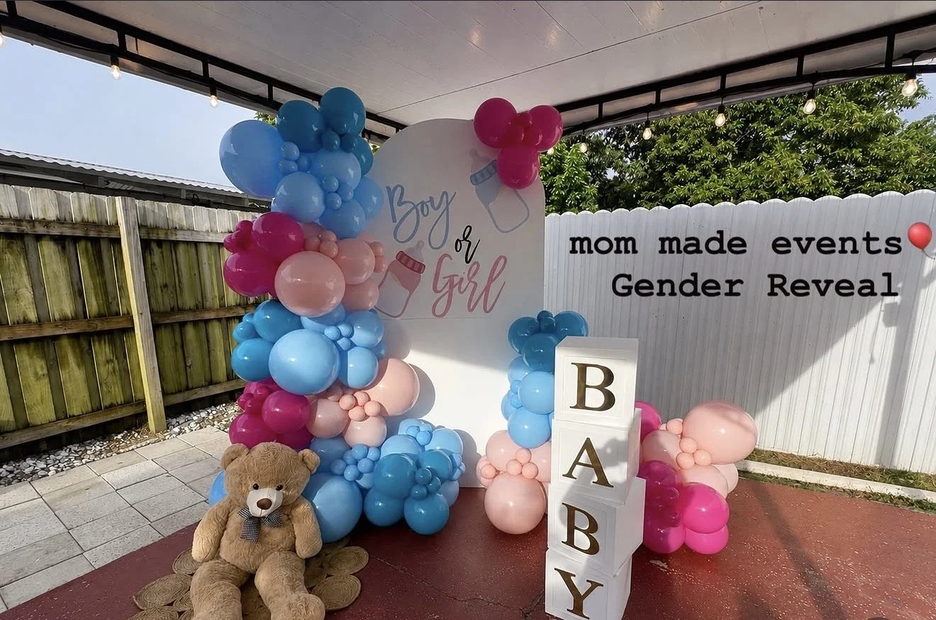 Baby gender reveal party setup with pink and blue balloons, a teddy bear, white blocks spelling 'BABY,' and a backdrop that reads 'mom made events Gender Reveal'