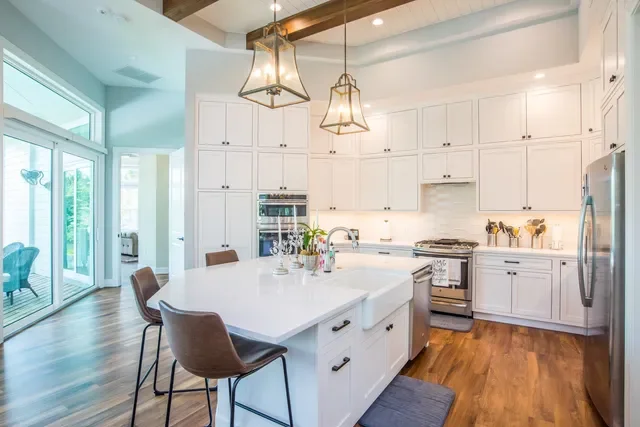 Modern kitchen with white cabinets, a large island with seating, stainless steel appliances, and pendant lighting.