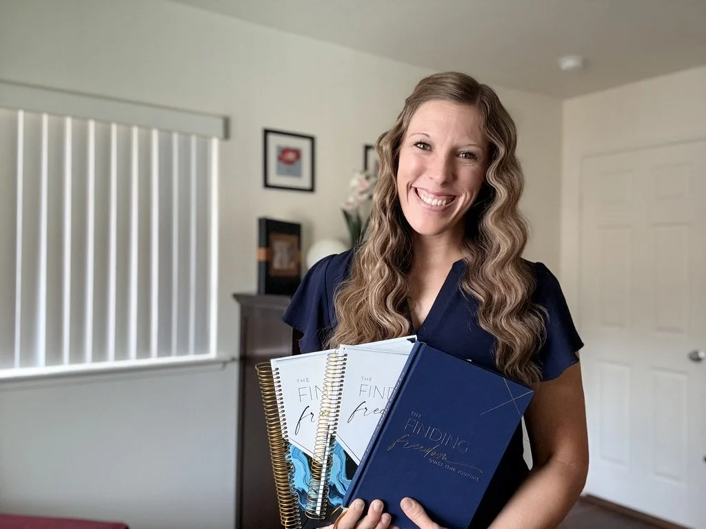 Woman smiling and holding three notebooks in a living room